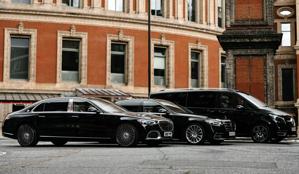 Two black luxury SUVs parked near an upscale urban building entrance.