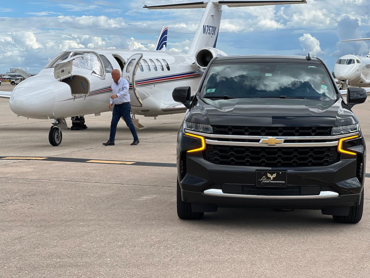 Black SUV with yellow running lights at an airport, ready for VIP transport.
