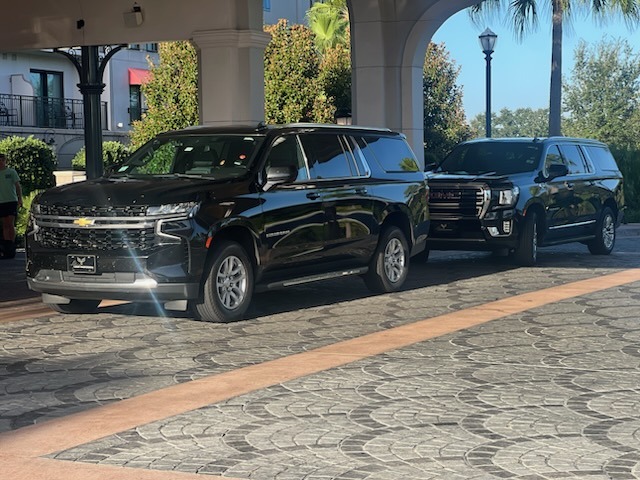 Luxury black SUV in front of a hotel driveway, ready for guest pickup.